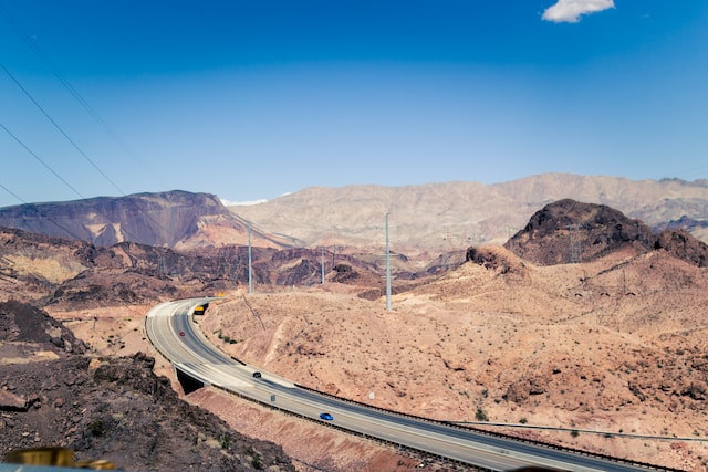 cars passing on highway overlooking hills and sand dunes