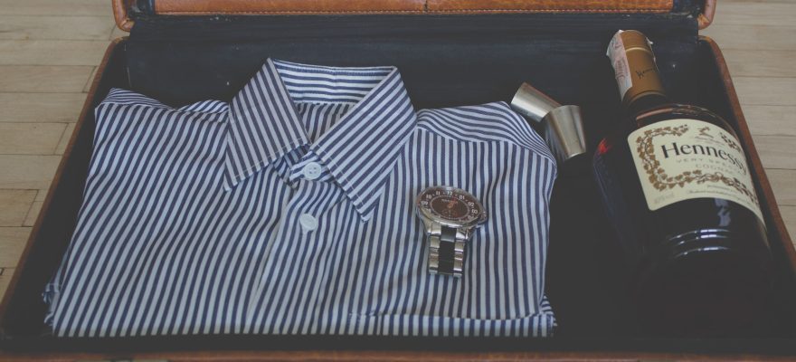 watch, whisky bottle and shirt in suitcase