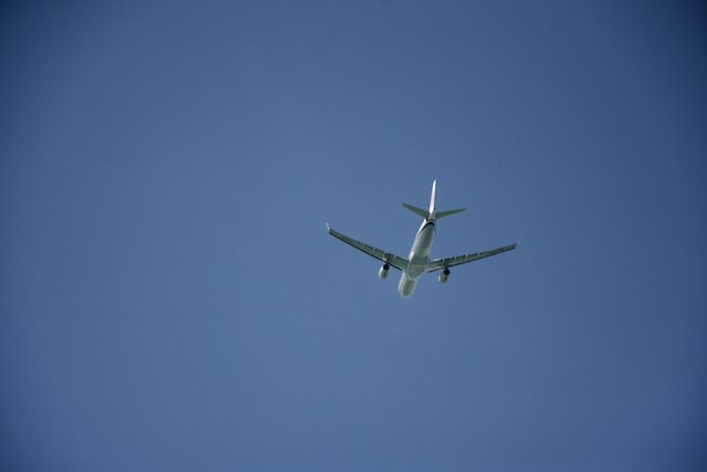 white airplane in mid air under blue sky
